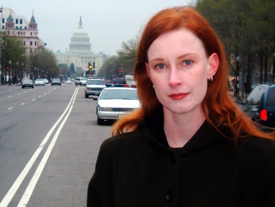 Woman with long, red hair standing in Washington street with Capitol Building in the background.