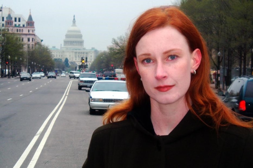 Woman with long, red hair standing in Washington street with Capitol Building in the background.