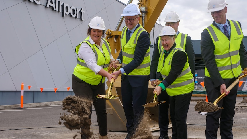 Prime Minister Anthony Albanese moves dirt with a shovel accompanied by three people
