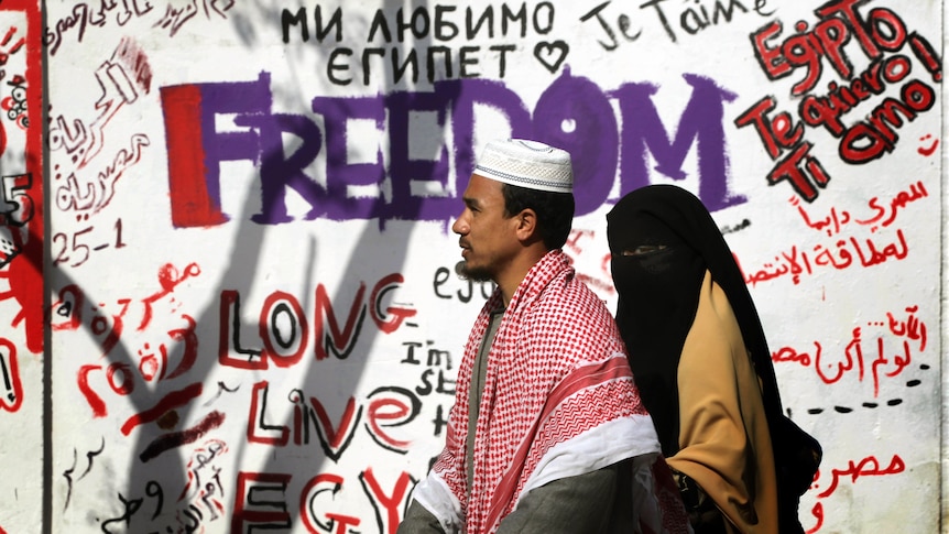 Egyptians walk past revolutionary graffiti on February 13, 2011 in Cairo, Egypt.