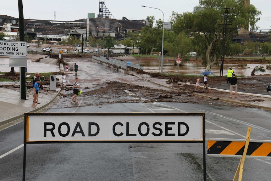 People look at mud and debris left on a bridge at Mount Isa, the water level is just under the bridge.