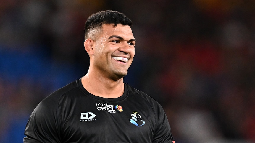 NRL player David Fifita smiles prior to a match, in a warm-up, wearing a black training shirt
