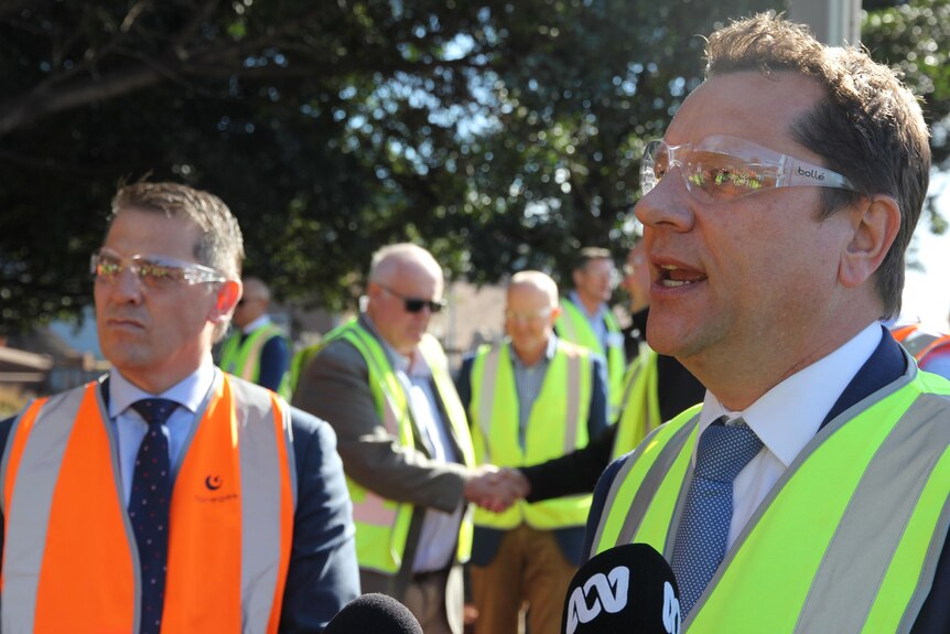 Two men is high vis and protective glasses - one is talking 