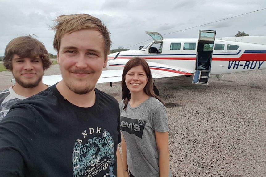 Julie Lelund, Alexander Jensen and Neikolaj Nielsen take a selfie with a plane in the background.