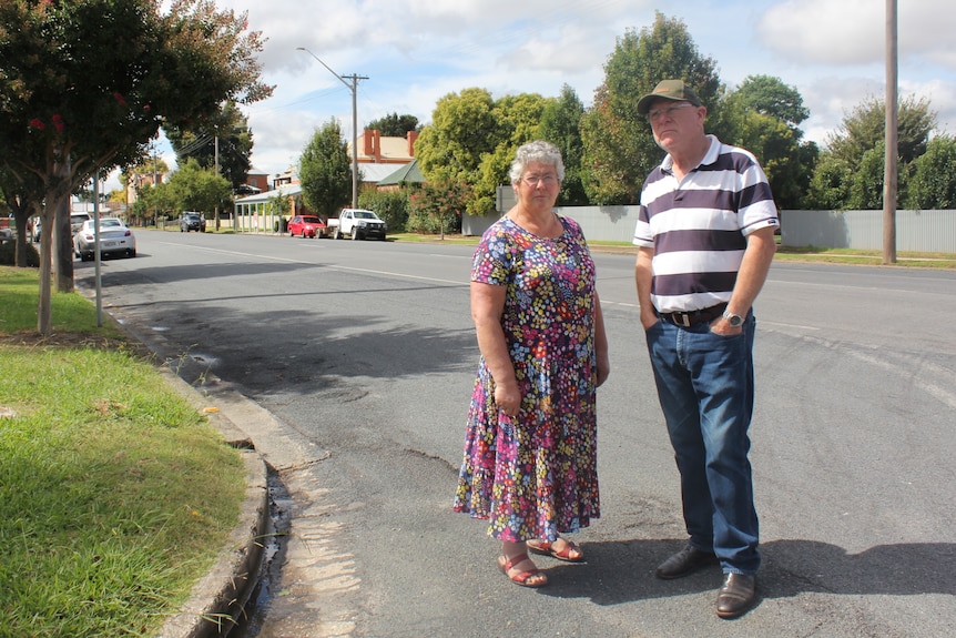 A man and woman stand on the side of a road