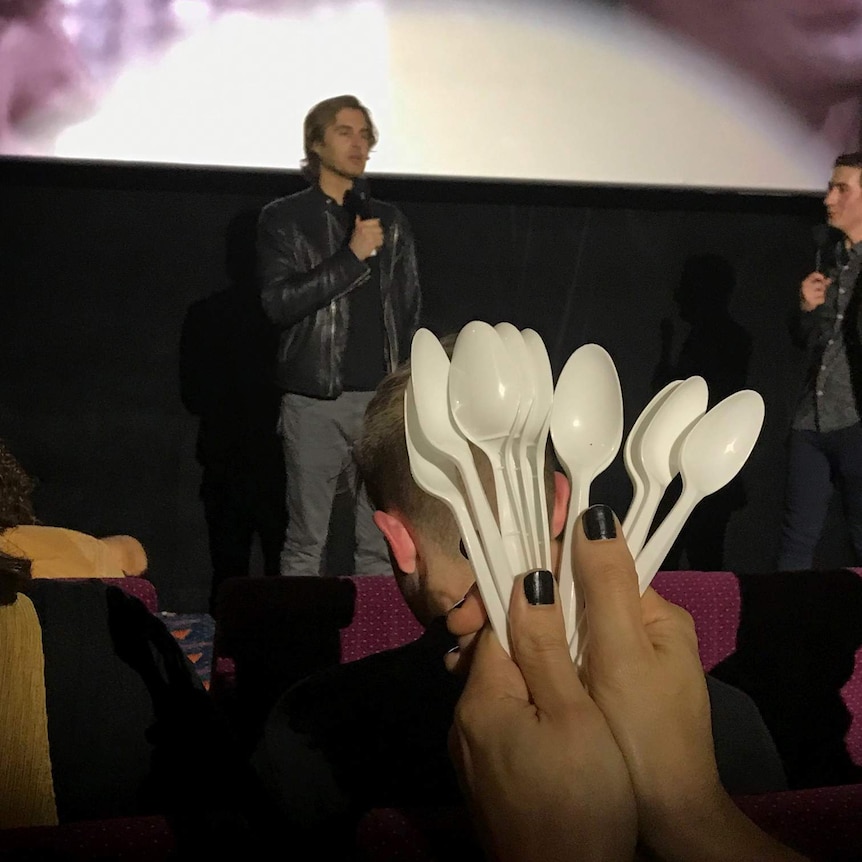 Greg Sestero talks as the crowd prepares to throw spoons at The Room