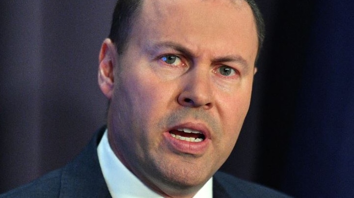 Josh Frydenberg making a speech, wearing a suit with an Australian flag while standing in front of an Australian flag.