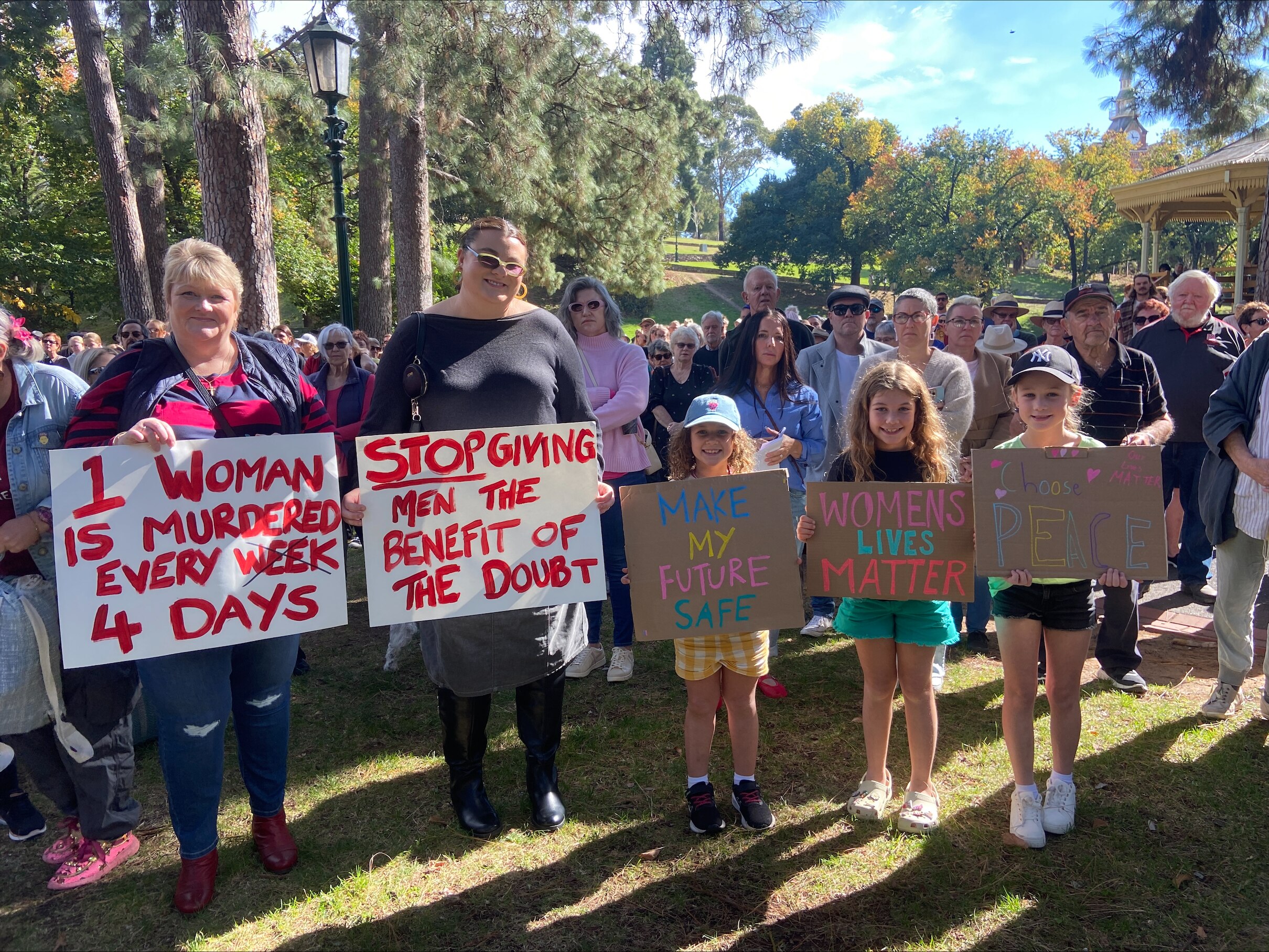A rally with women holding signs advocating against violence