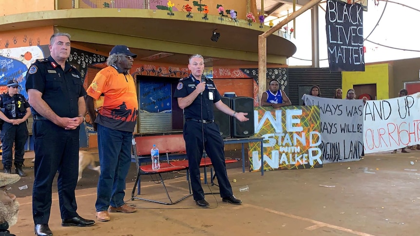 Travis Wurst stands in front of banners as he addresses the Yuendumu community.