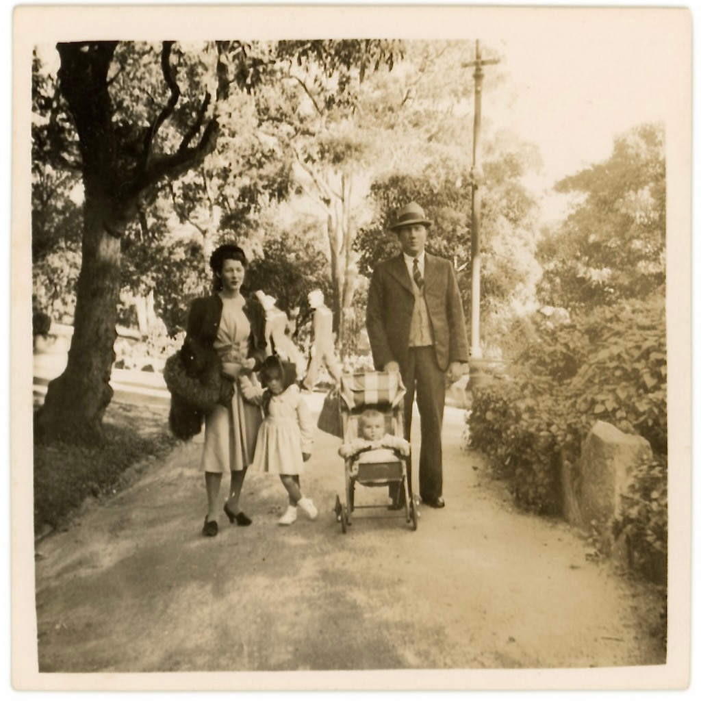 Um casal com um filho pequeno e um carrinho de bebê caminha pela rua na década de 1940