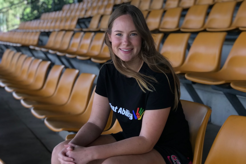 Lauren Cheatle sits in a chair in a grandstand and smiles.