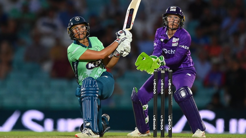 Suzie Bates plays a shot as wicketkeeper Alyssa Healy looks on during a cricket game.