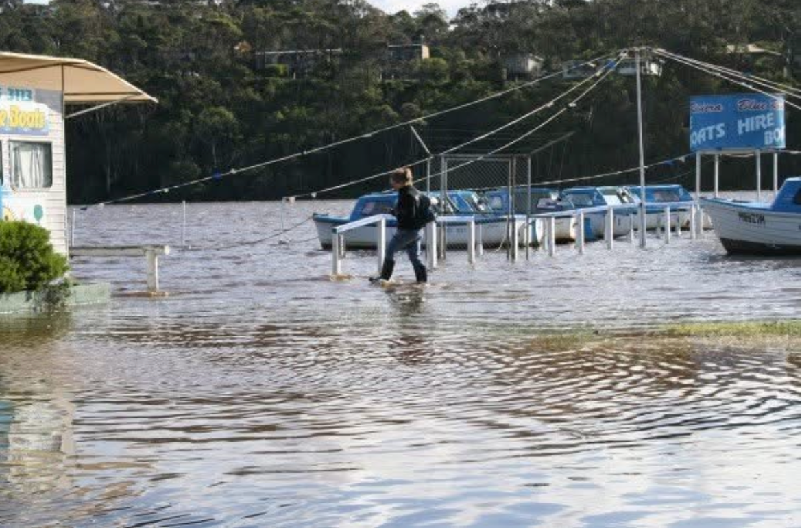woman walking through flood waters near jetty