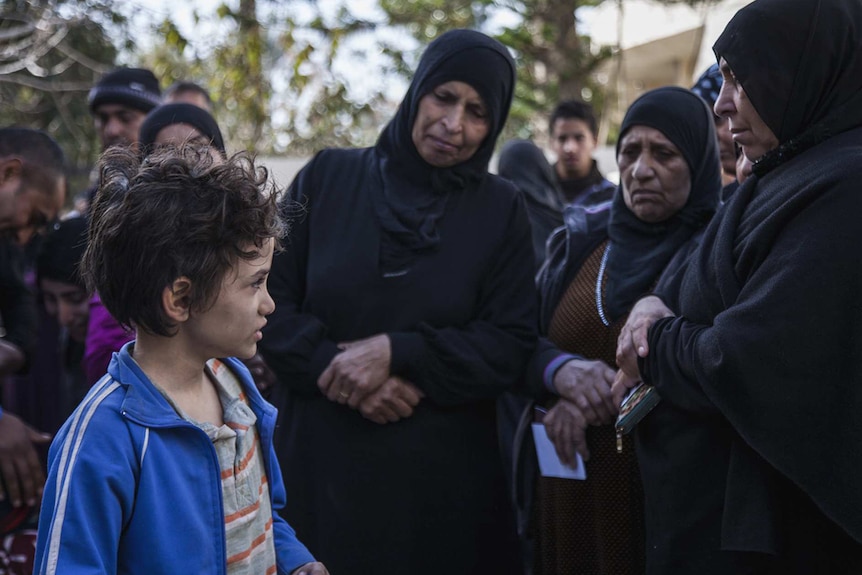 Colour photo of Zain Al Rafeea surrounded by group of women in 2018 film Capharnaüm.