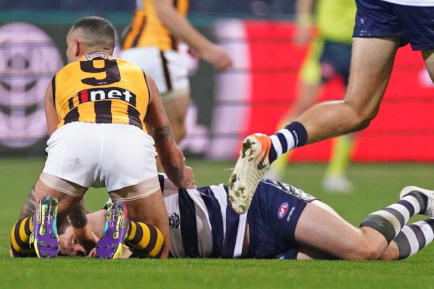 Shaun Burgoyne is on his knees next to Patrick Dangerfield, who is lying face down and looking a little dazed