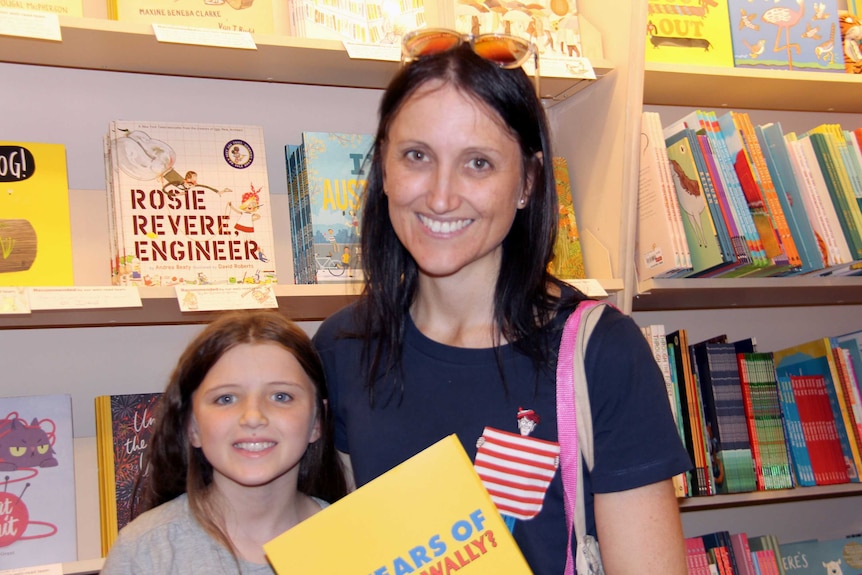 Nicole and sarah holding up Wally books.