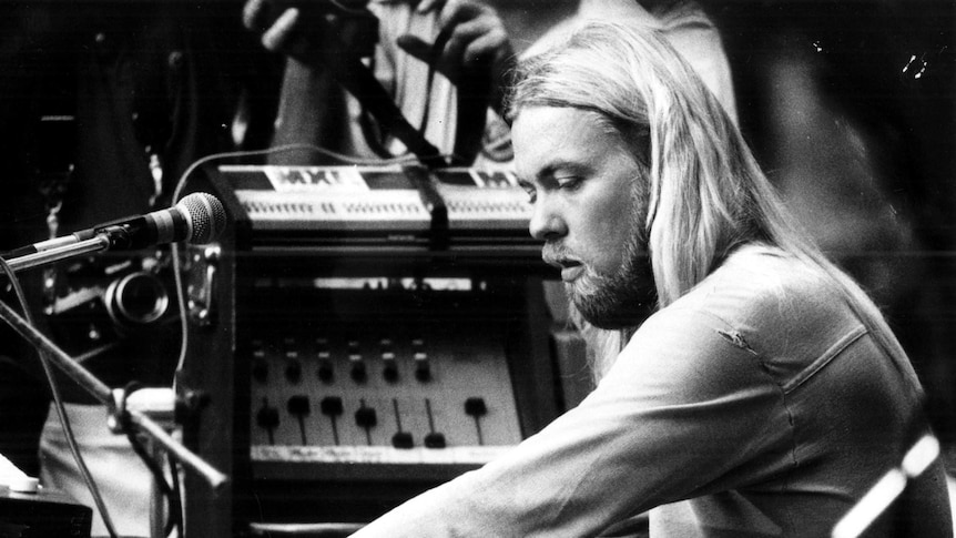 Gregg Allman plays the organ at a concert in a black and white photo.