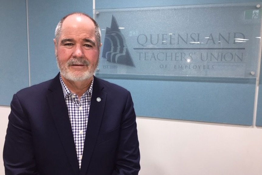 Kevin Bates stands alongside a sign at Queensland Teachers Union in Brisbane.