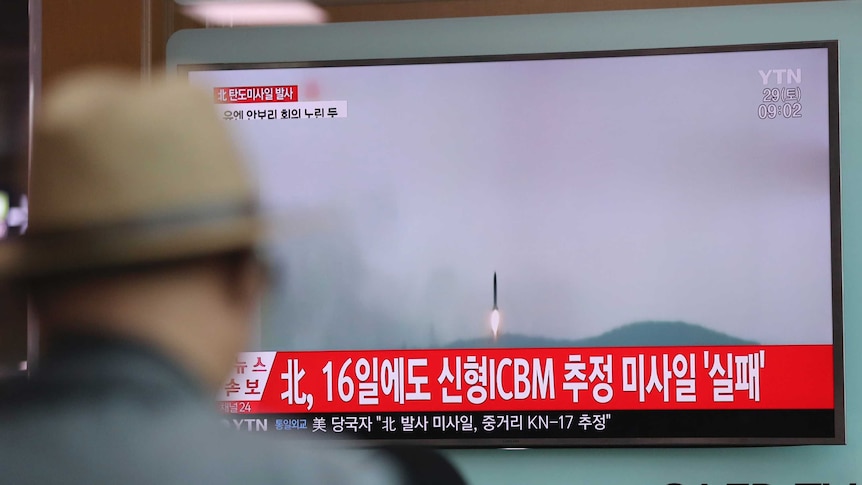 A man watches breaking news, with footage showing a missile being fired, on a TV at a South Korean train station.
