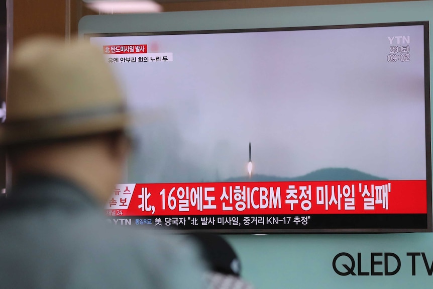 A man watches breaking news, with footage showing a missile being fired, on a TV at a South Korean train station.