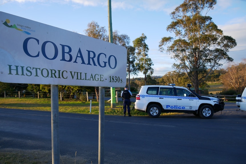 the sign of Cobargo in the foreground with a cop car in the backcground