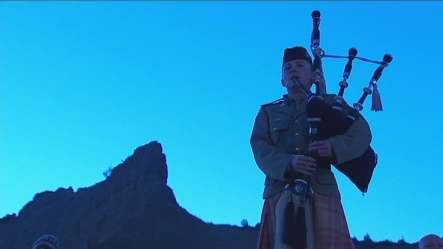A bag piper standing in front of rocks at Gallipoli plays at the dawn service