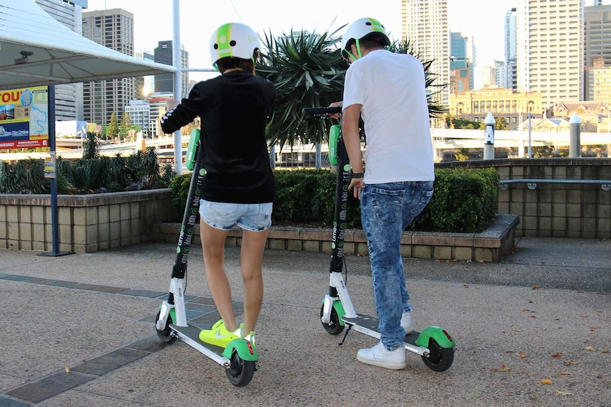Two people riding on Lime scooters at South Bank in Brisbane