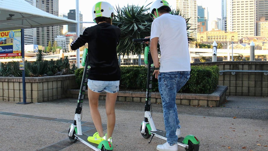 Two people riding on Lime scooters at South Bank in Brisbane