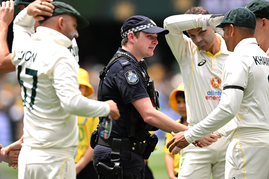 a police officer shakes the hand of Australian test cricketers after a moment's silence