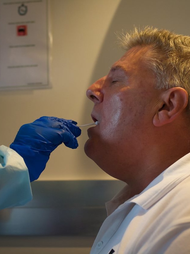 A man with his mouth open as he undergoes a swab test of his throat for coronavirus.