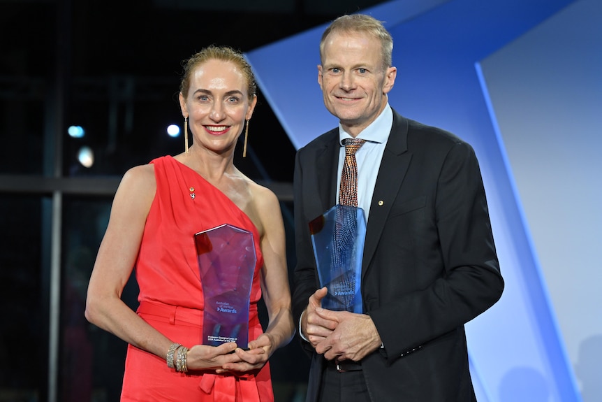 A woman and a man dressed formally with awards.