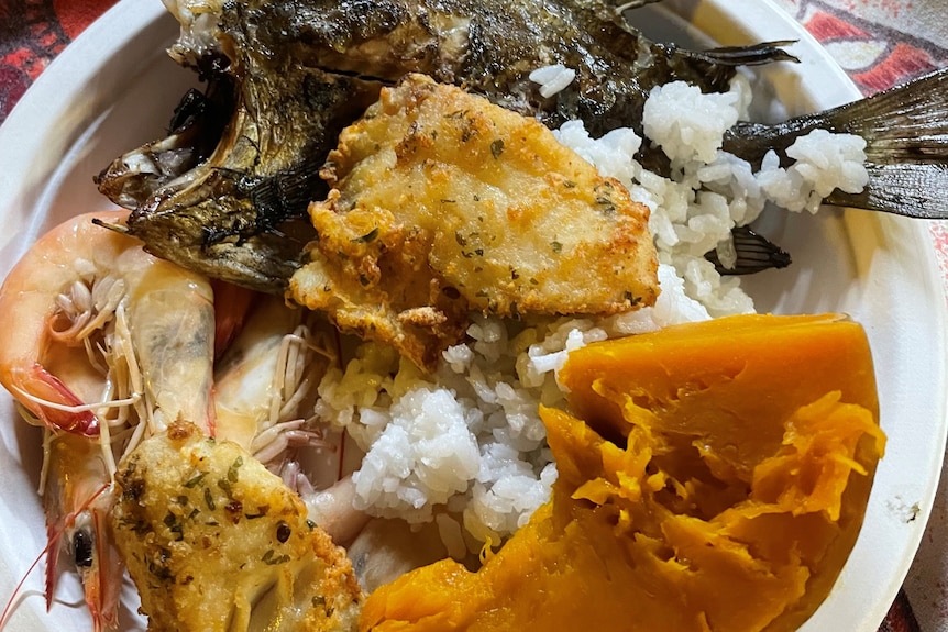 Plate of food with cooked fish and prawns.