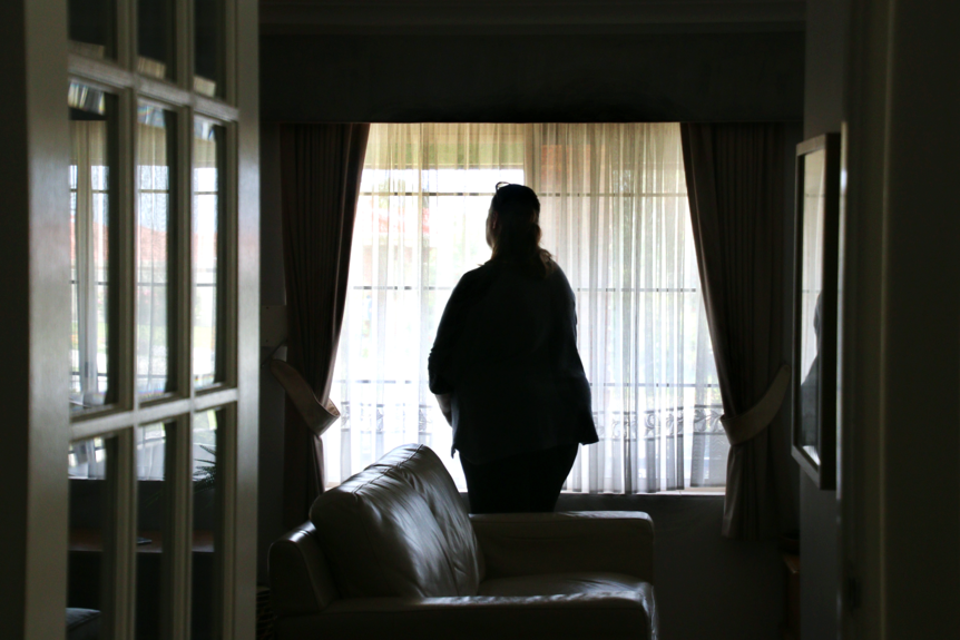 A woman pictured from behind as she looks out the window
