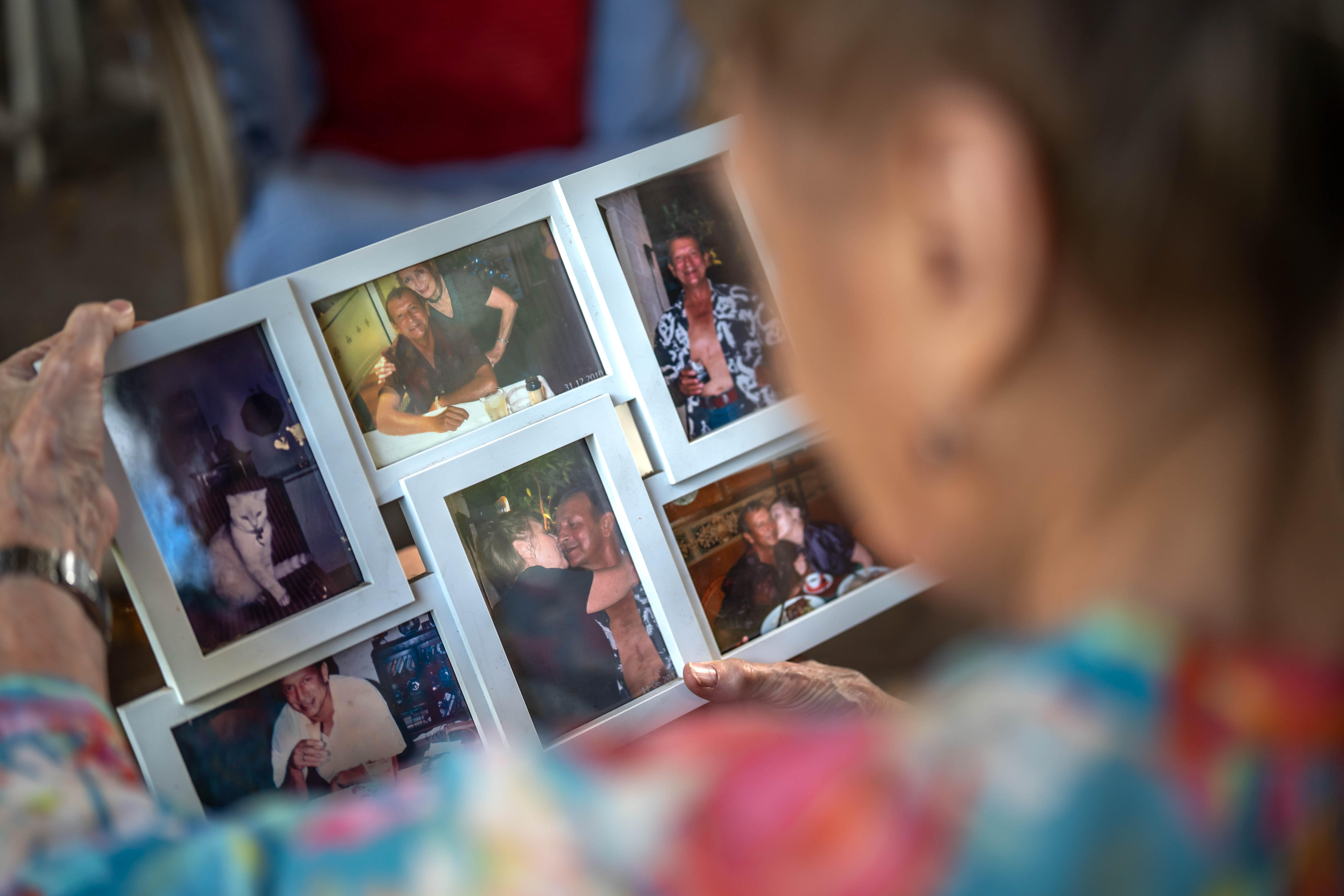 An over the shoulder shot of a woman holding a six photo frame with multiple photos of her and her partner.