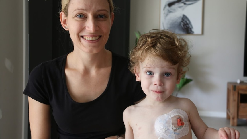 A woman and her small son who has a chest catheter held in place by tape.