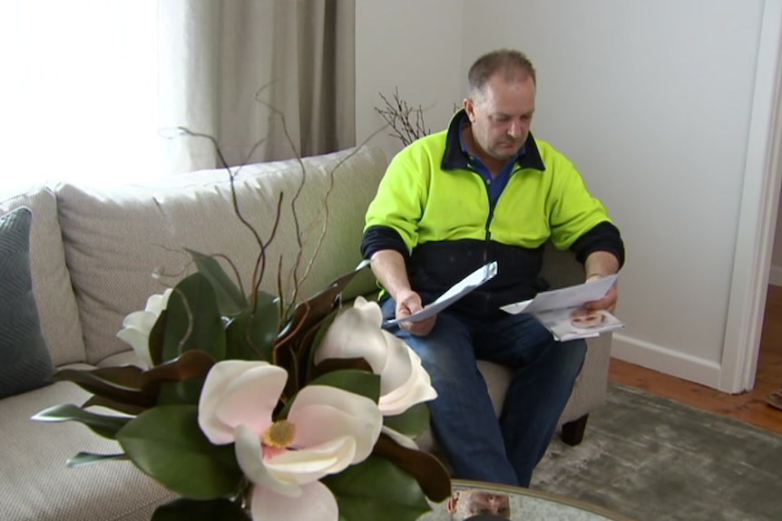 A man seated in a lounge chair holding some paperwork.