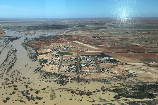 An aerial photo of a small town next to a flooded brown river