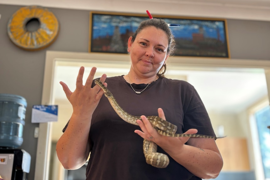 A woman in a black shirt holds a snake. 