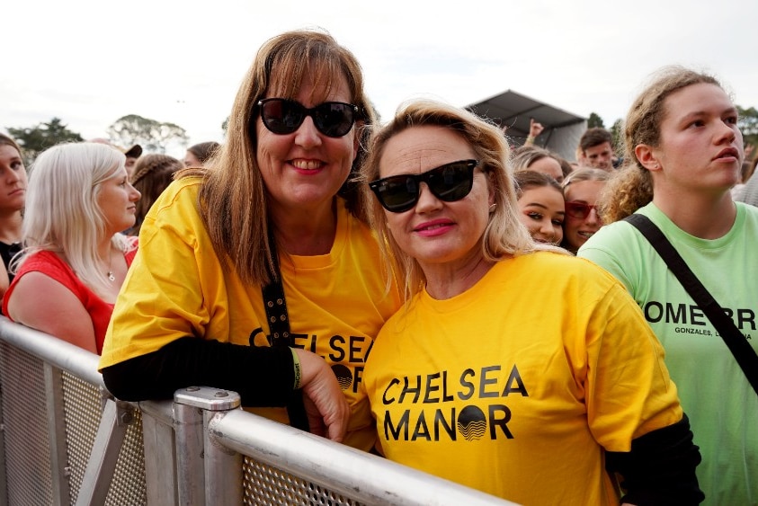 Family of Chelsea Manor pose for a photo in the crowd in their bright yellow band shirts.