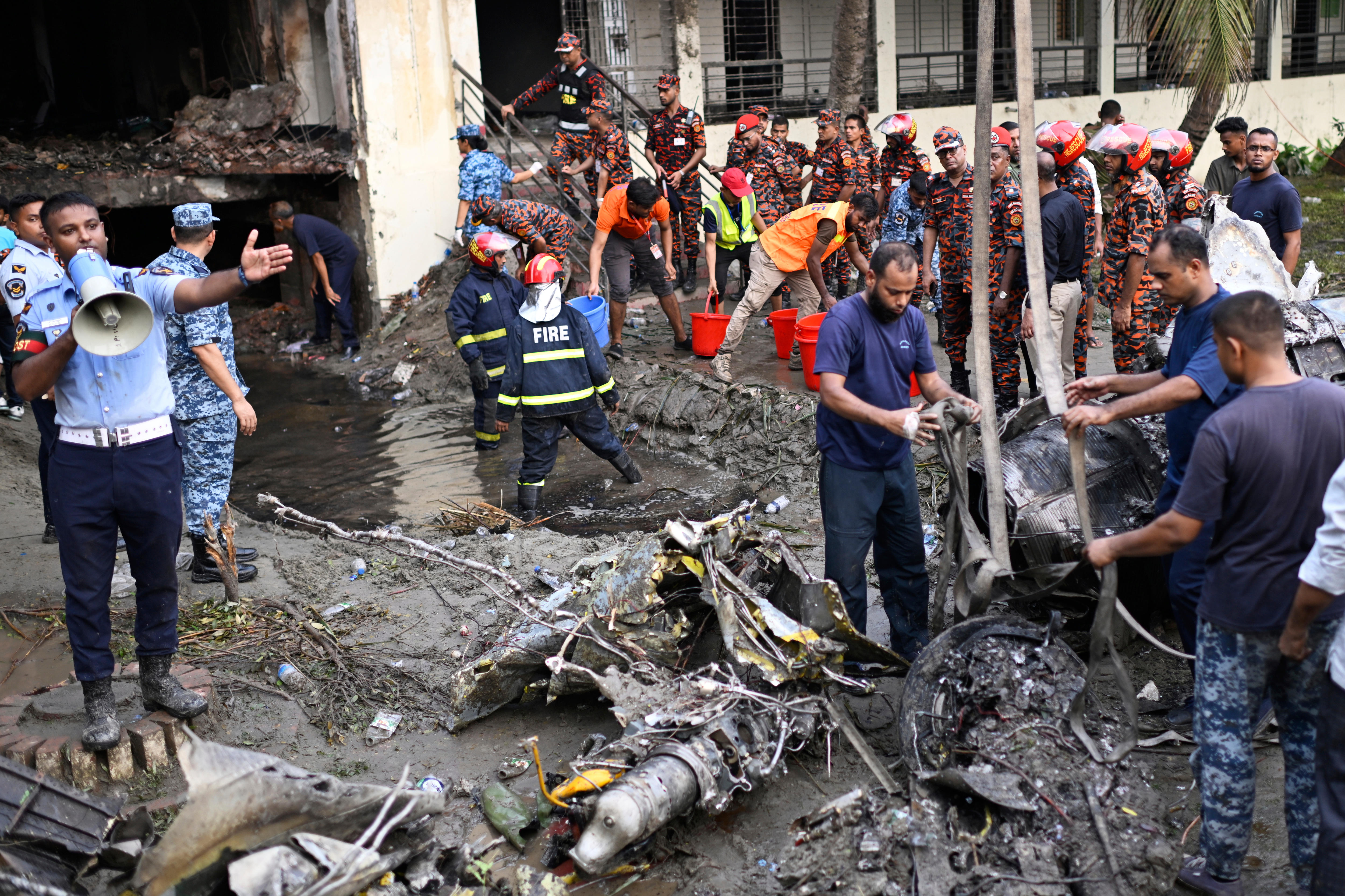 Firefighters and emergency personnel standing around the ashen wreckage of a fighter jet