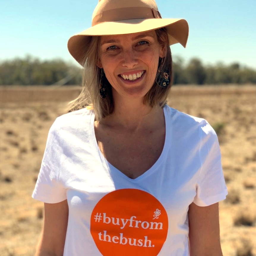 Grace Brennan stands in a paddock with a shirt reading #buyfromthebush