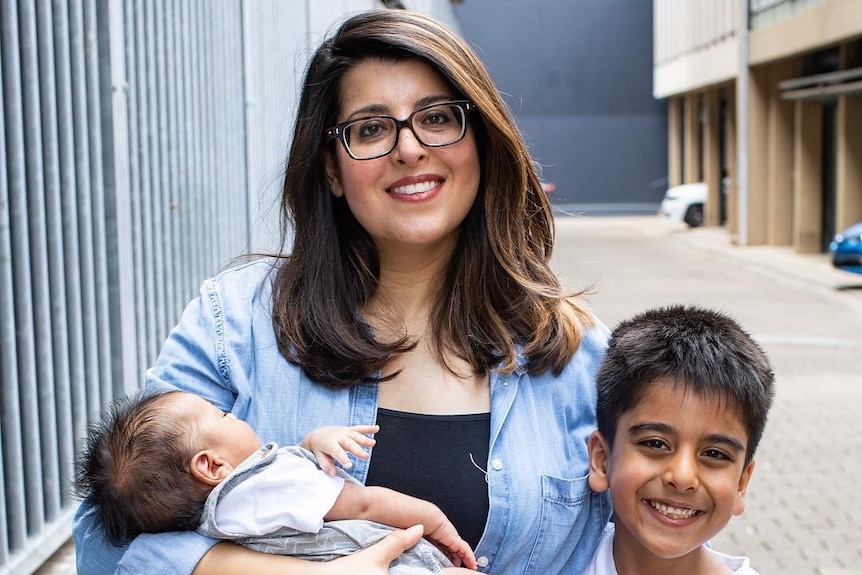 A smiling woman in glasses with her two sons.