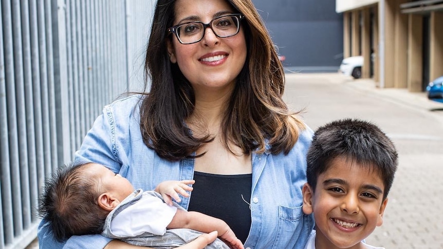 A smiling woman in glasses with her two sons.