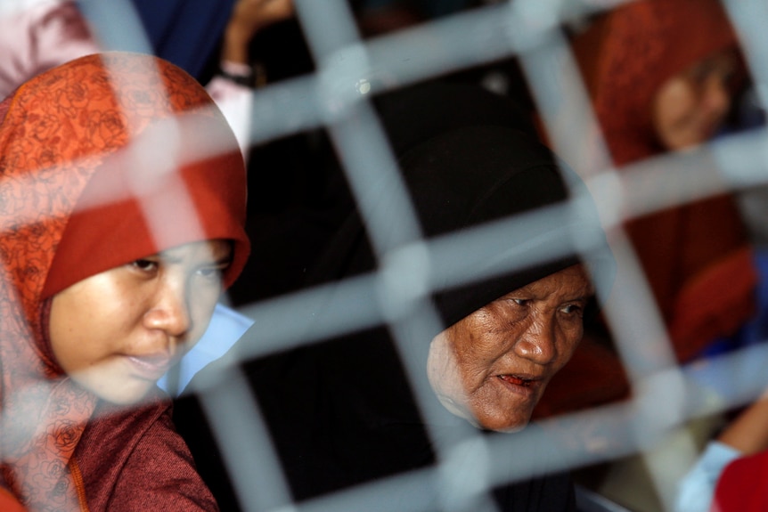 Two women in hijabs seen through wire