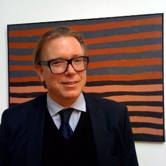 A man wearing a suit and glasses in front of the work
