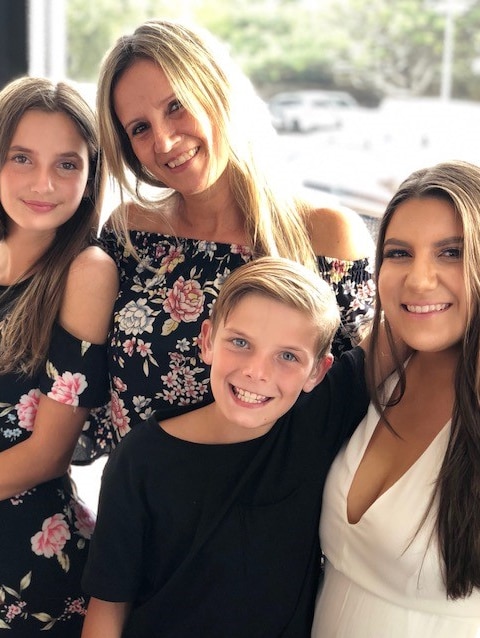 A family photo of a mother and three children smiling.