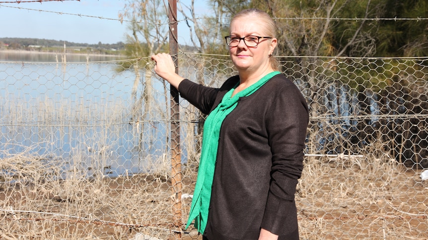 Michelle Vearing stands hold onto a wire fence in front of Lake Wyangan in Grifftih.