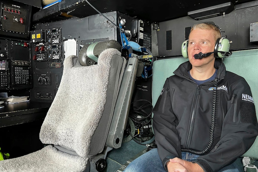 크리스 헵킨스 뉴질랜드 총리가 헤드셋을 착용하고 헬리콥터에 앉아 있다.