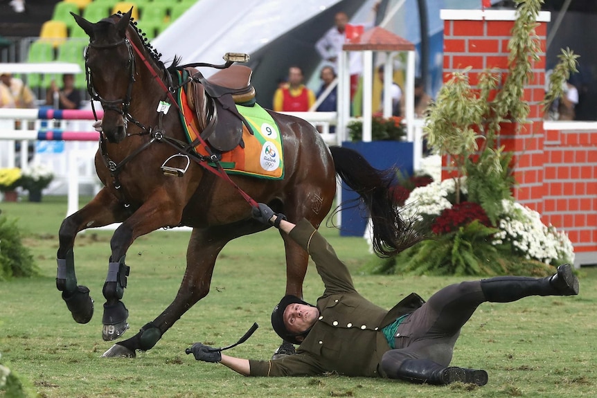 Justinas Kinderis of Lithuania falls during the show jumping round of Modern Pentathlon on Day 15 of the Rio 2016 Olympic Games.
