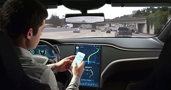 A man uses his mobile phone while his driverless car transports him on a highway.